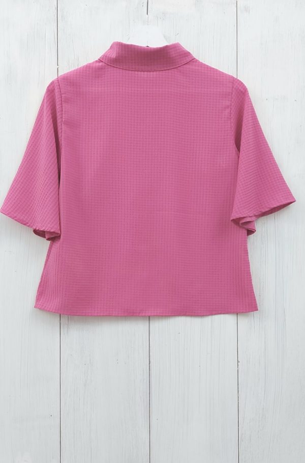 Camisa rosa Zinia de Lylu en tejido de bambula. Lleva mangas cortas acampanadas y cierre con botones en la parte delantera.