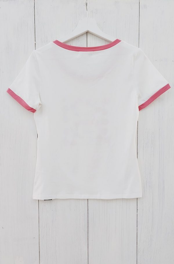 Camiseta blanca Begonia de Lylu de mangas cortas y escote redondo, con estampación de cerezas en el delantero. Detalle de ribetes de cuello y mangas en rosa.